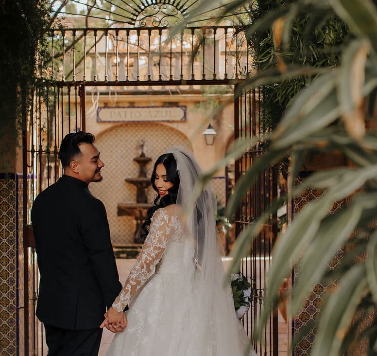 Bride and groom holding hands beneath the Patio Azul gate
