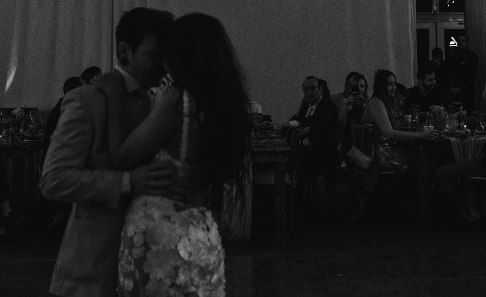 Couple slow dancing at a candlelit reception in black and white