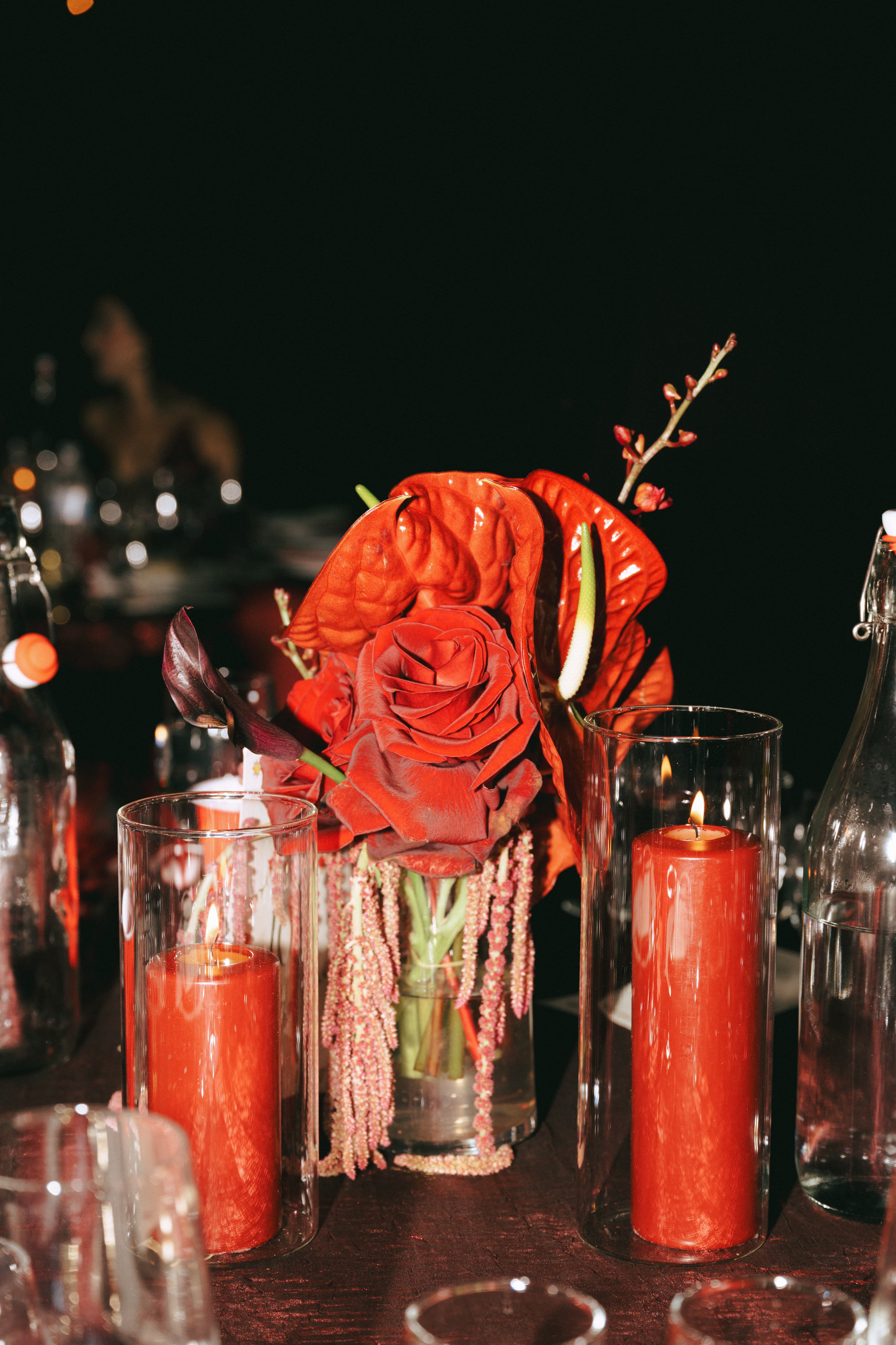 Dark red-on-black wedding tablescape with red roses, beaded centerpieces, and red pillar candles in glass hurricanes
