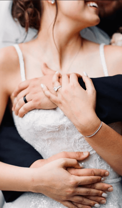 Close-up of the couple's hands and rings during an embrace