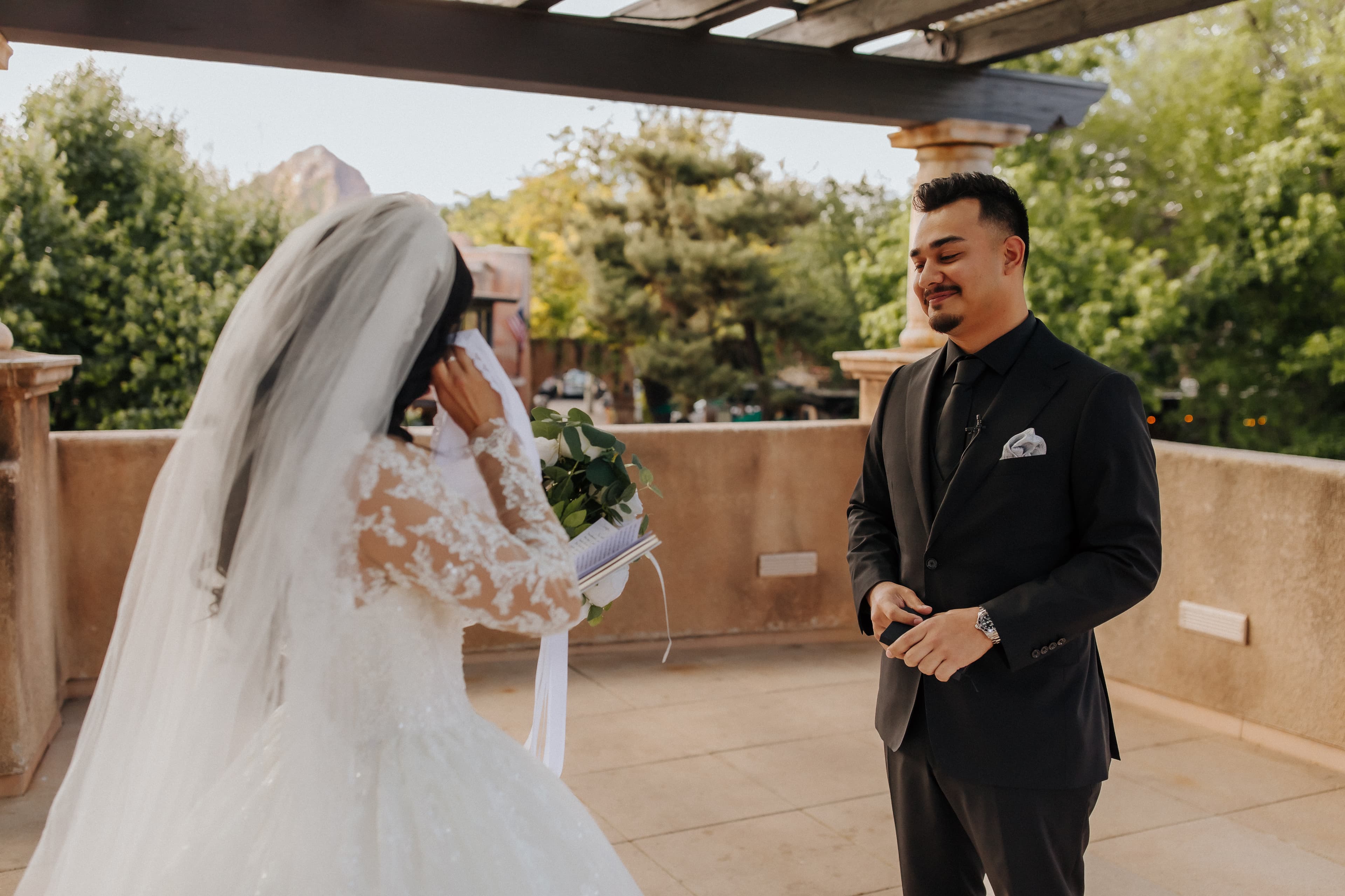 Bride wiping away a tear during the first look on a terrace