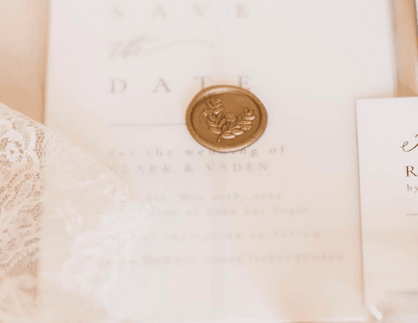 Save-the-date card with a gold wax seal and lace detail