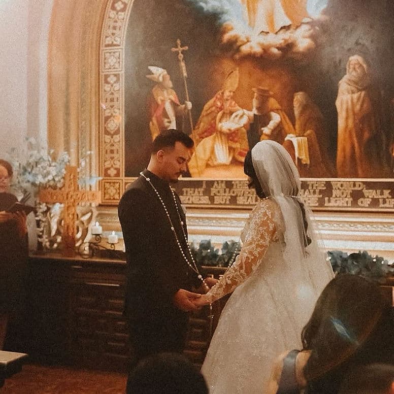 Bride and groom exchanging vows in a candlelit historic chapel