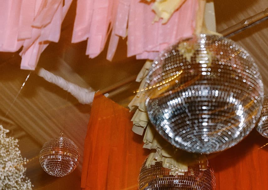 Disco balls and pink streamers hanging from a reception ceiling