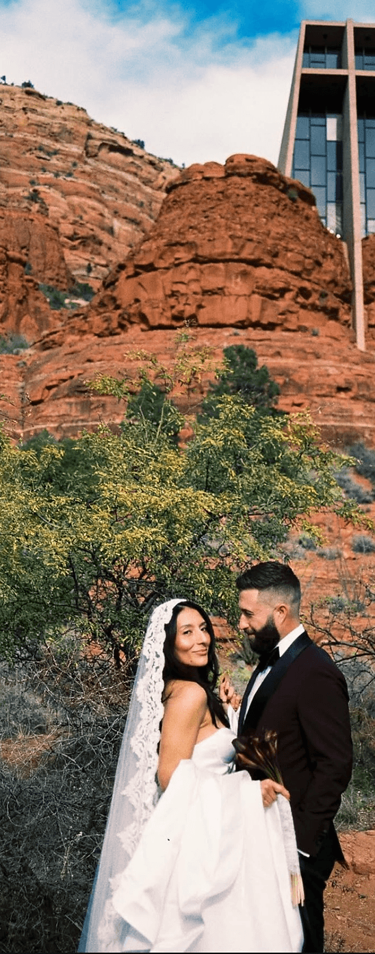 Bride and groom beneath the Chapel of the Holy Cross in Sedona's red rocks