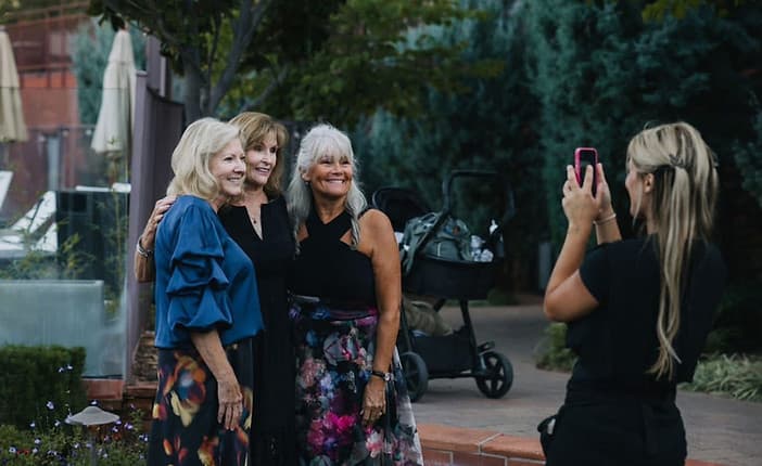 Arabella taking photos of three wedding guests in a garden