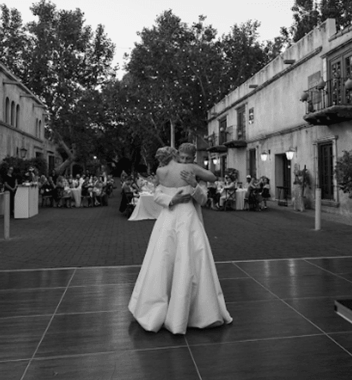 Bride and groom sharing a slow dance in a historic courtyard under string lights, black and white