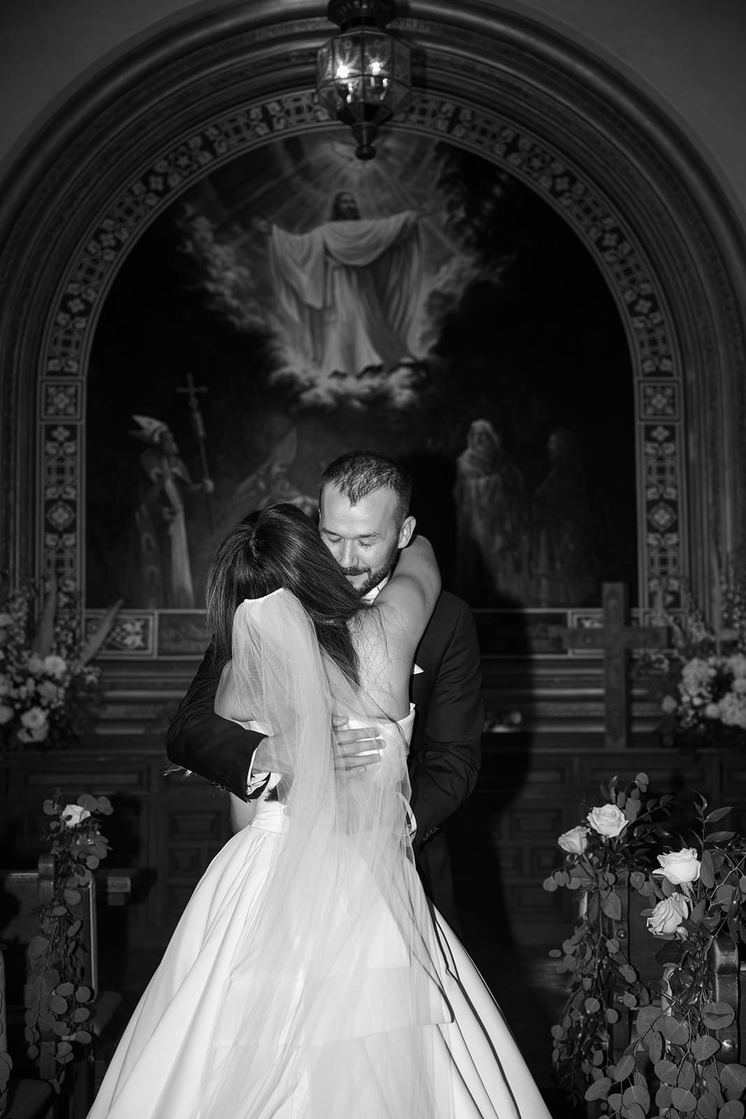 A long embrace before the altar, in black and white
