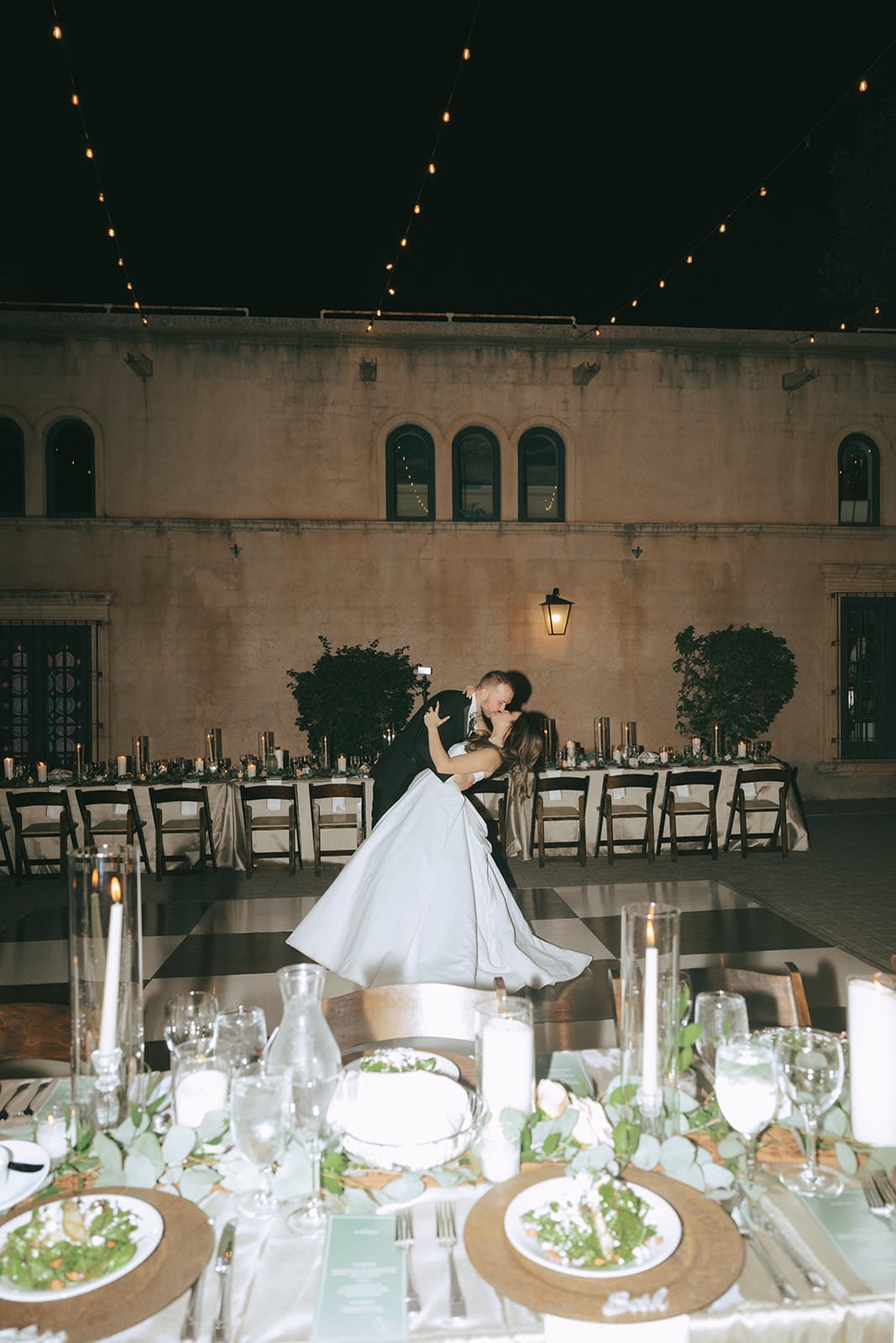 Connor dipping Abby into a kiss on the checkered dance floor beneath string lights in the Tlaquepaque Calle