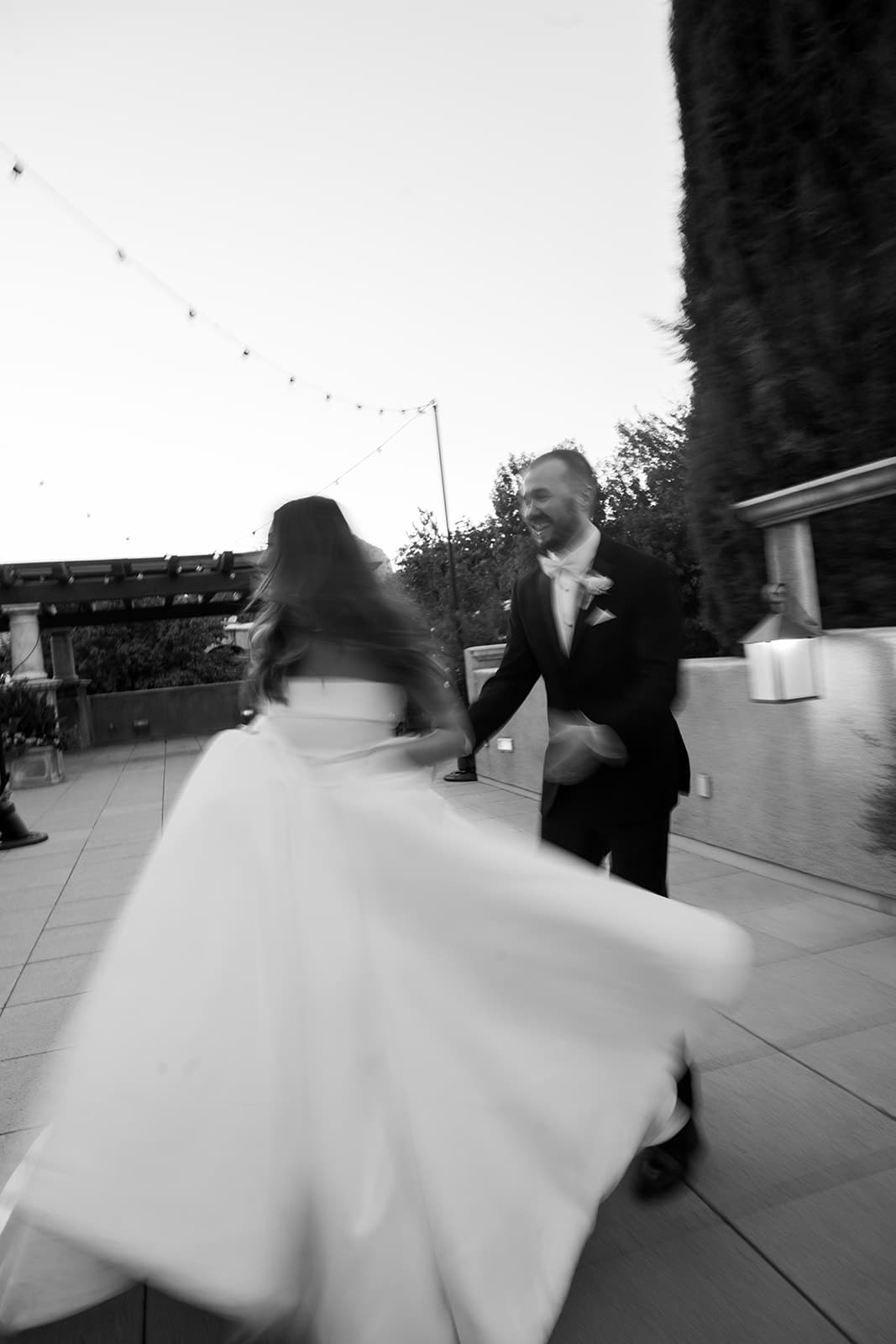 Abby and Connor running hand in hand across a terrace, in black and white
