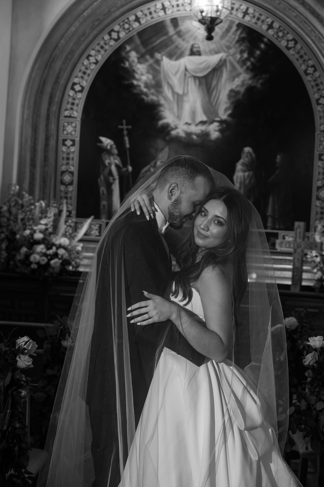 Wrapped together beneath the veil before the chapel altar, in black and white