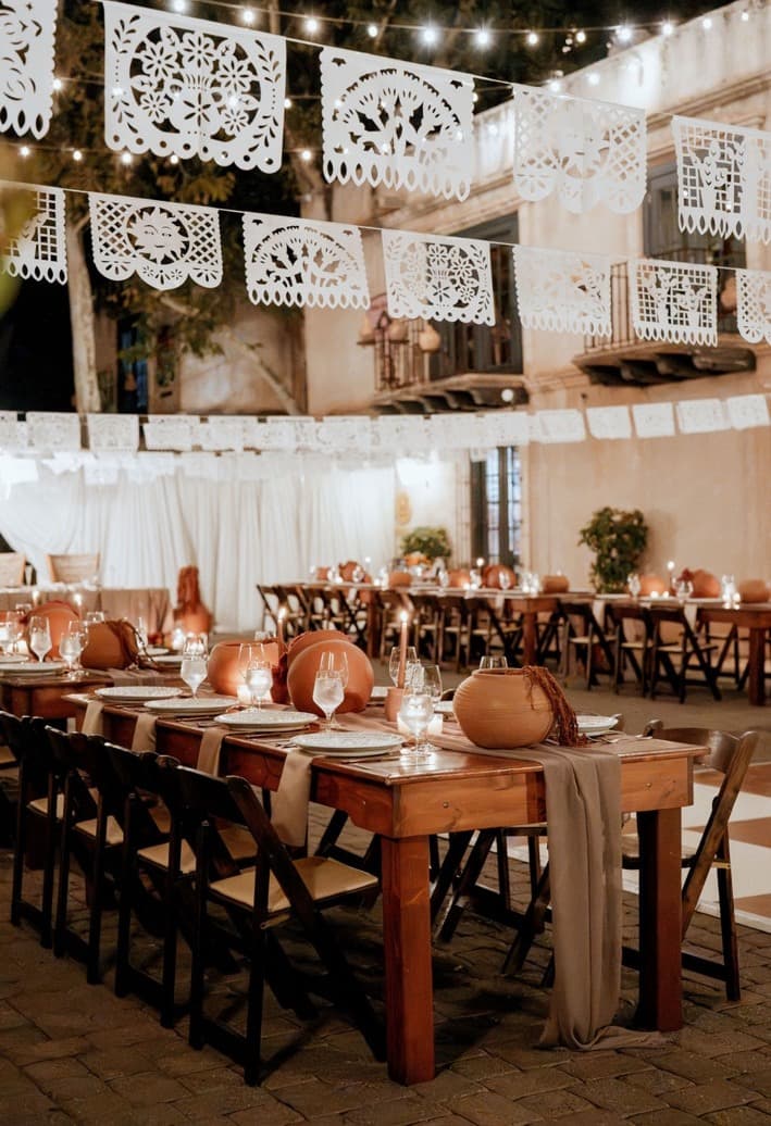 Banquet tables with taupe runners and terracotta pottery lining the Tlaquepaque courtyard