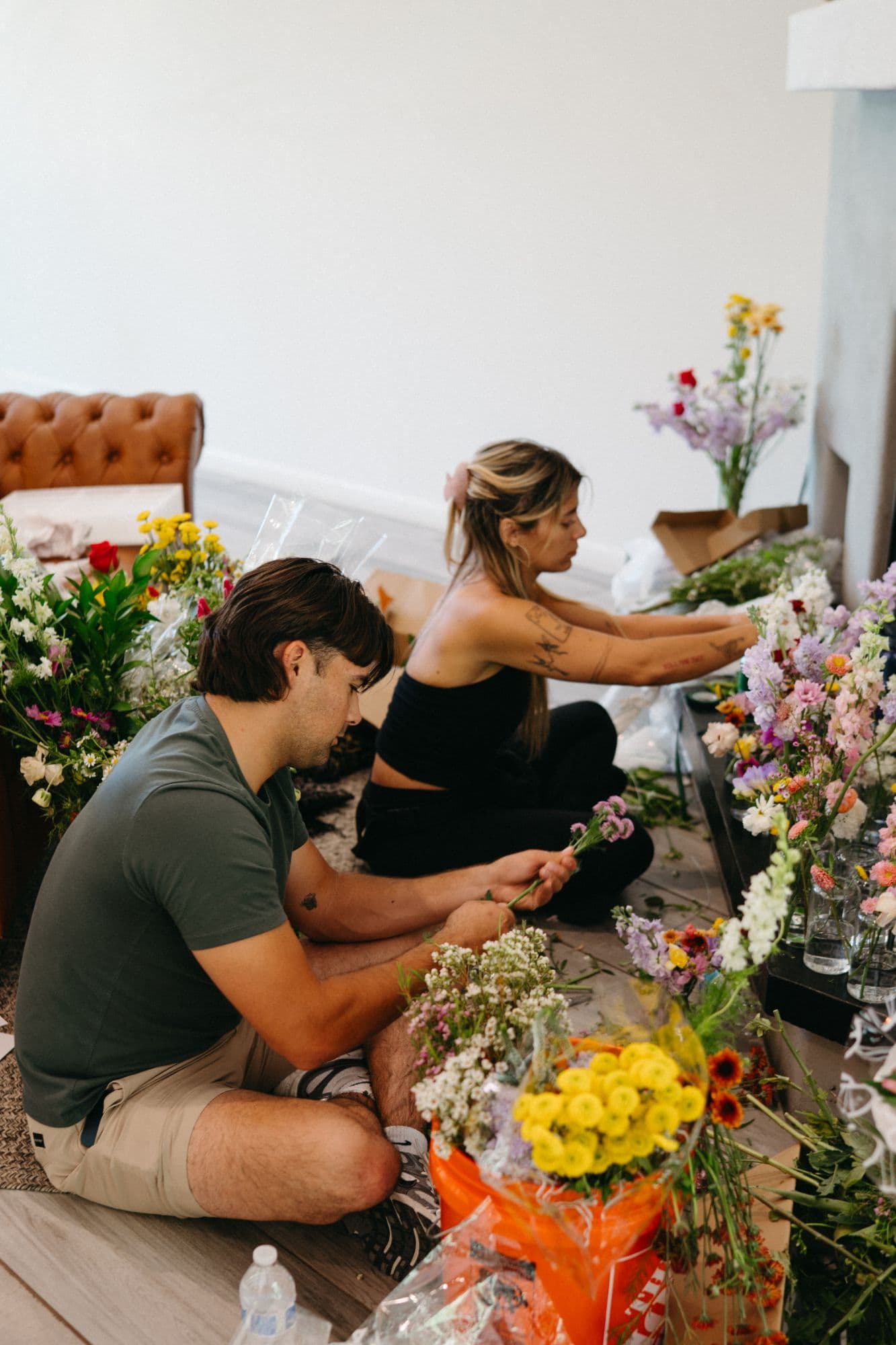 Malu and Arabella arranging wildflowers into rows of glass bud vases