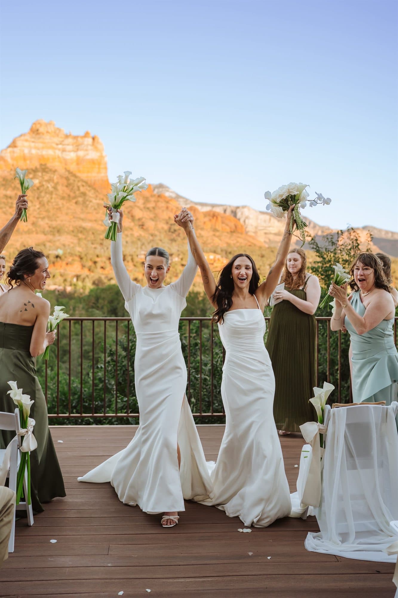 Brynn and Megan raising their calla lily bouquets in celebration before the Sedona red rocks