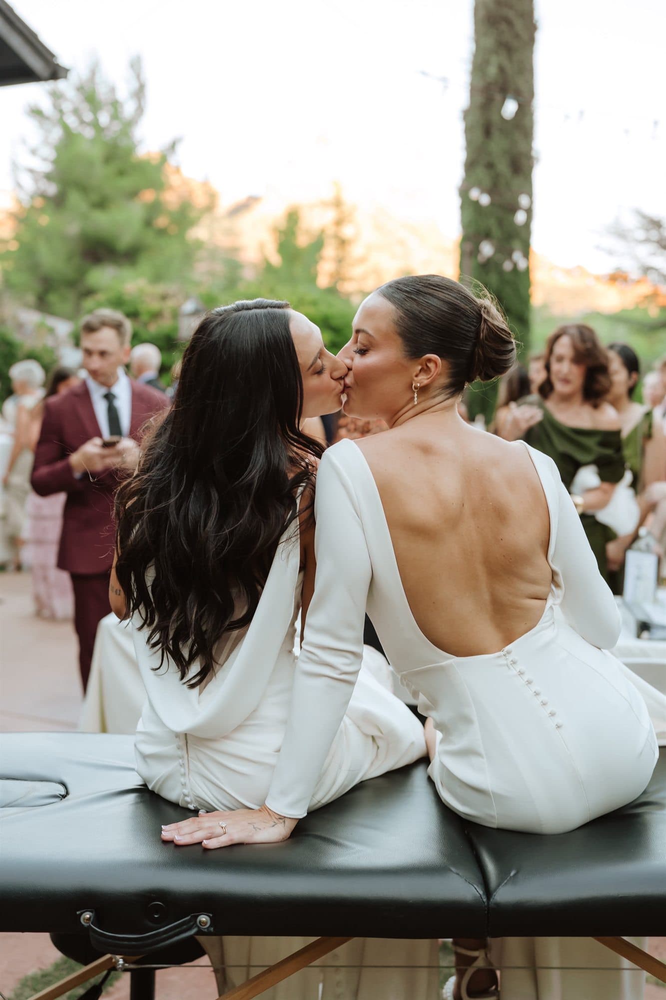 Brynn and Megan sharing a kiss while sitting together at the tattoo station
