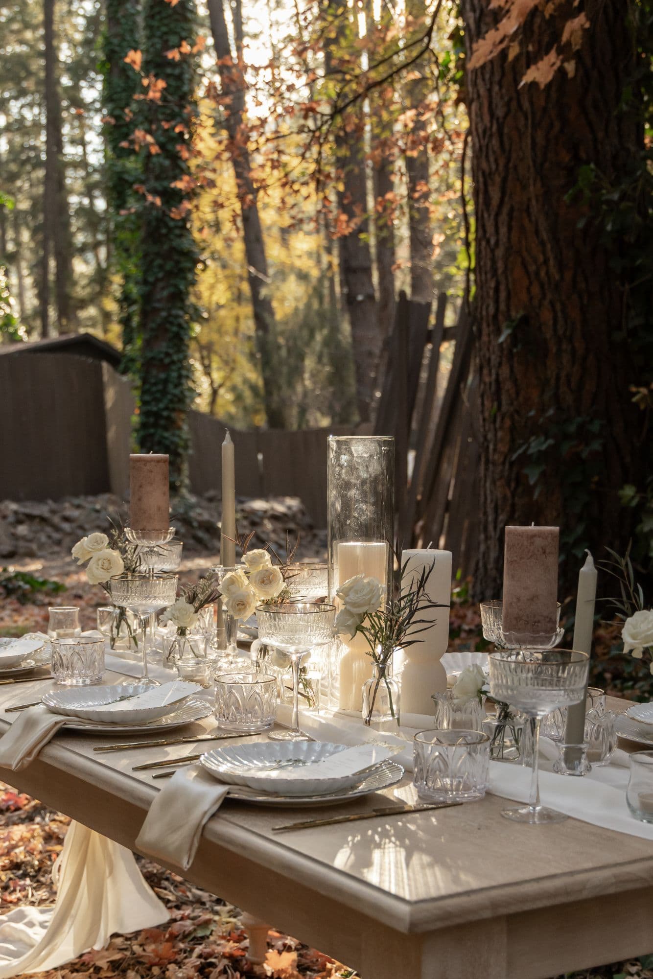 Ivory and mauve candlelit tablescape under towering autumn trees