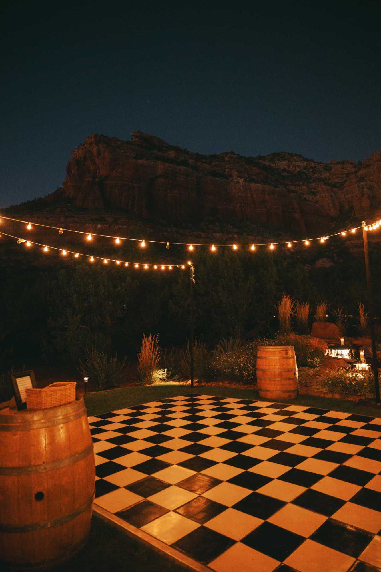 Checkered dance floor under string lights with the Sedona red rocks behind it at night