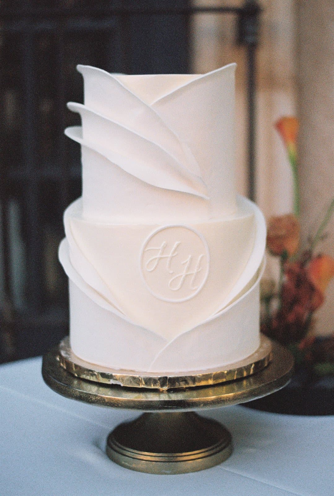 A sculptural ivory wedding cake with the couple’s monogram