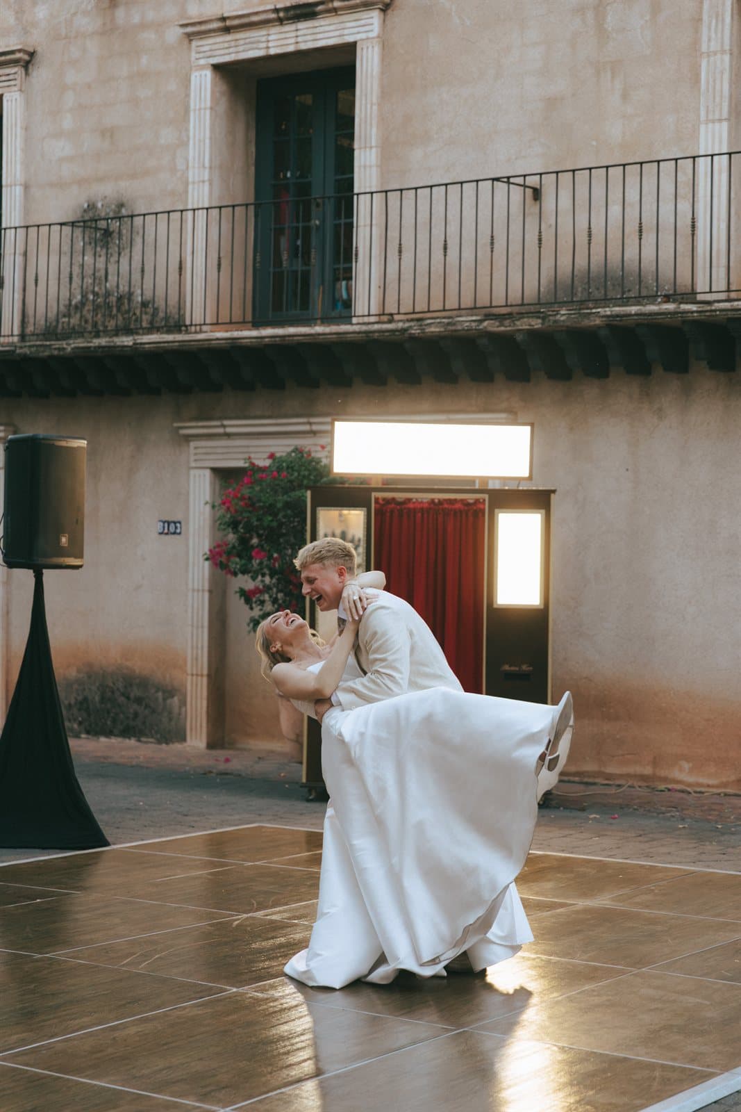 A groom twirling his bride before a vintage photo booth