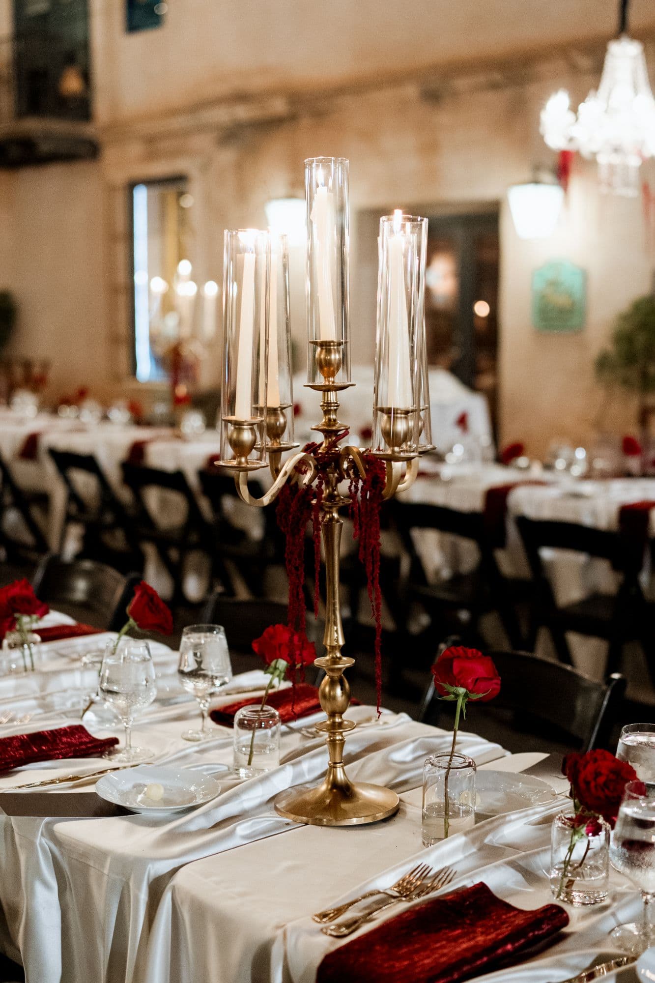 Gold candelabra with taper candles in glass hurricanes on a reception table