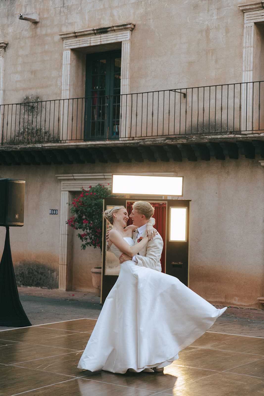 Hunter lifting Hannah in a joyful first dance in front of a vintage photo booth