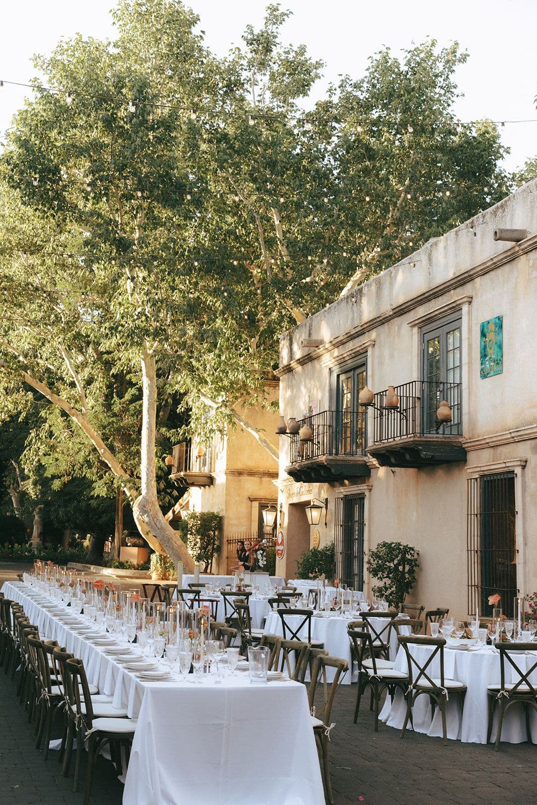Reception tables under string lights between courtyard balconies