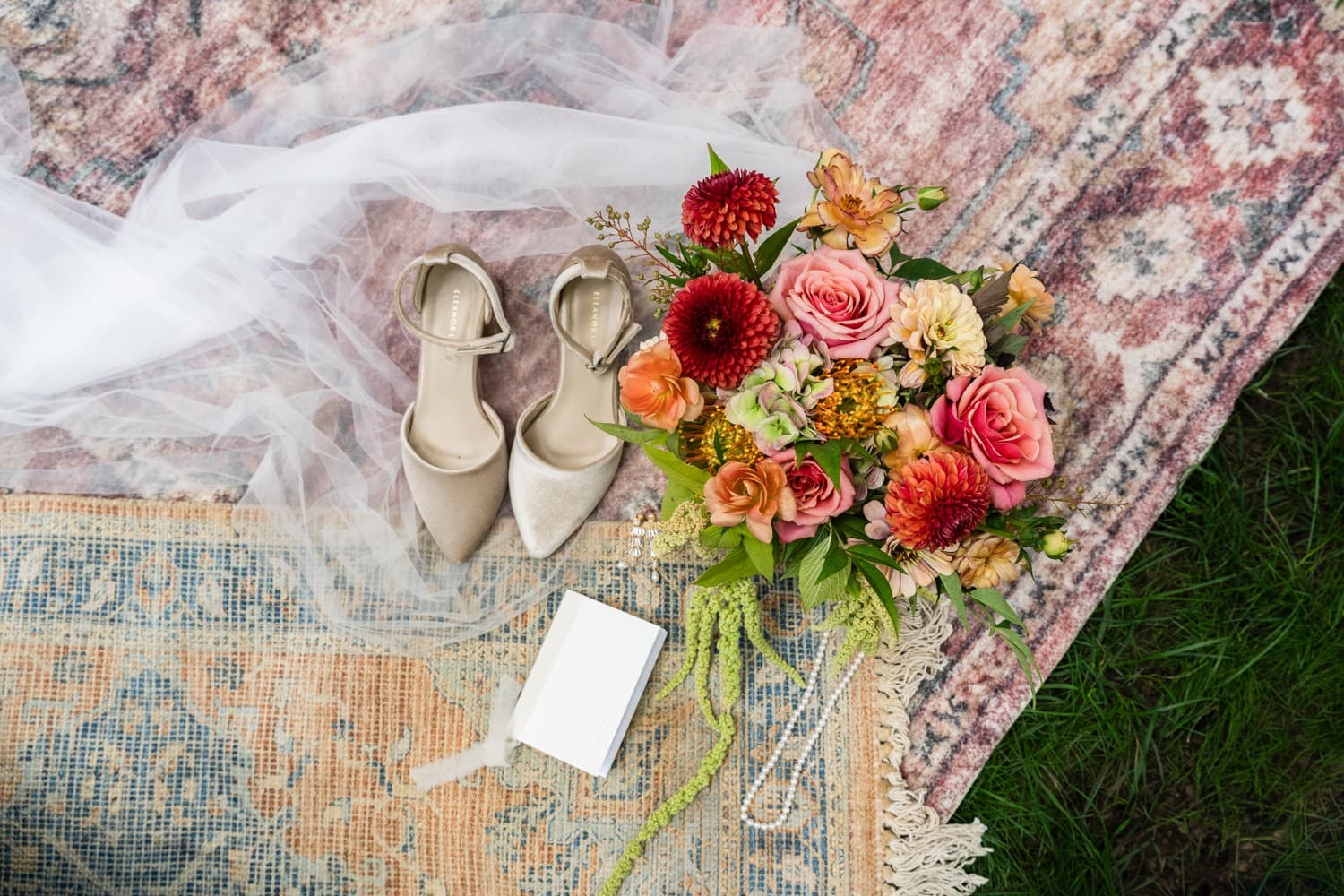 Velvet heels, pearls, vows and a bouquet of dahlias, roses and hanging amaranthus on layered vintage rugs
