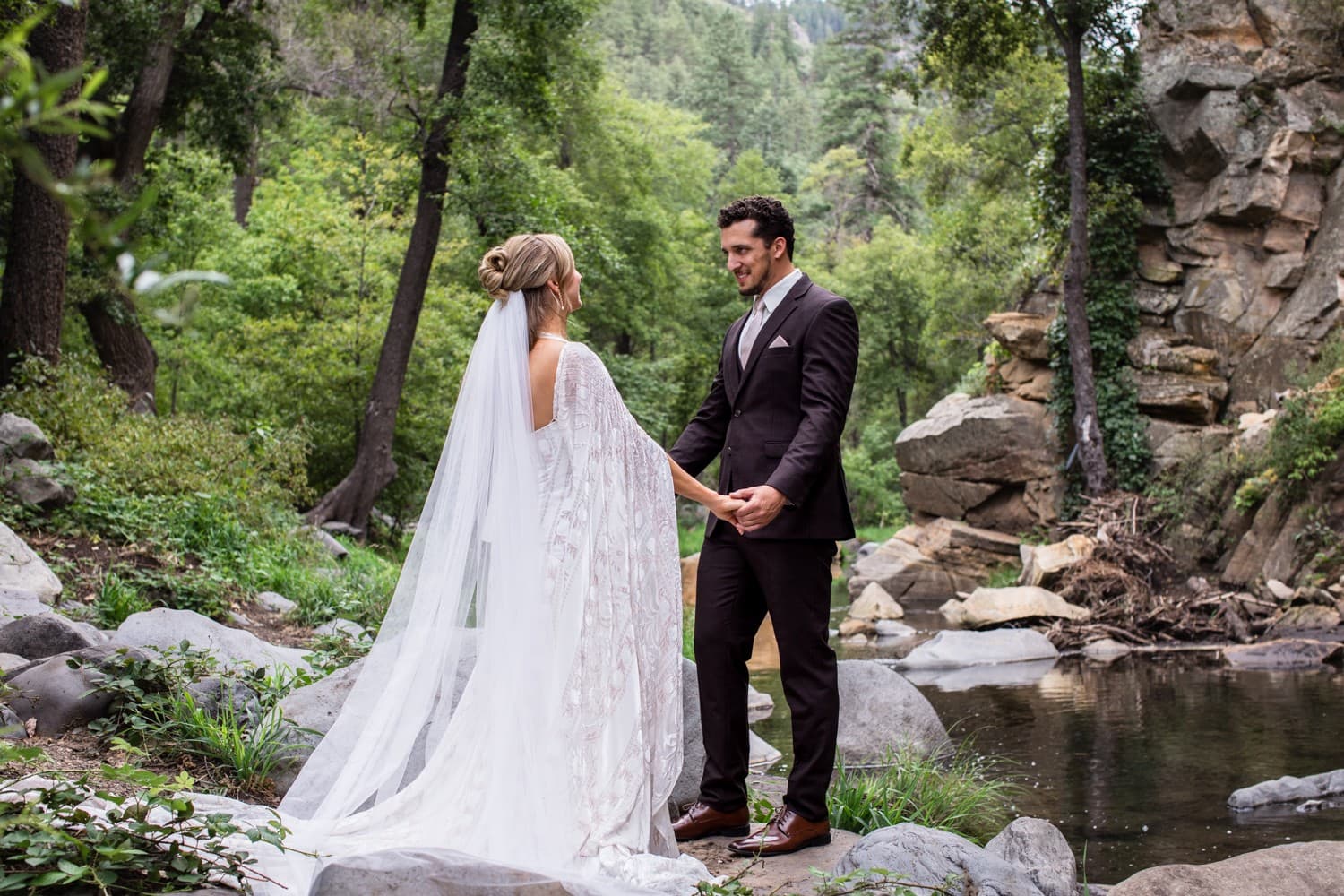 Hannah and Michael holding hands at their first look beside the creek