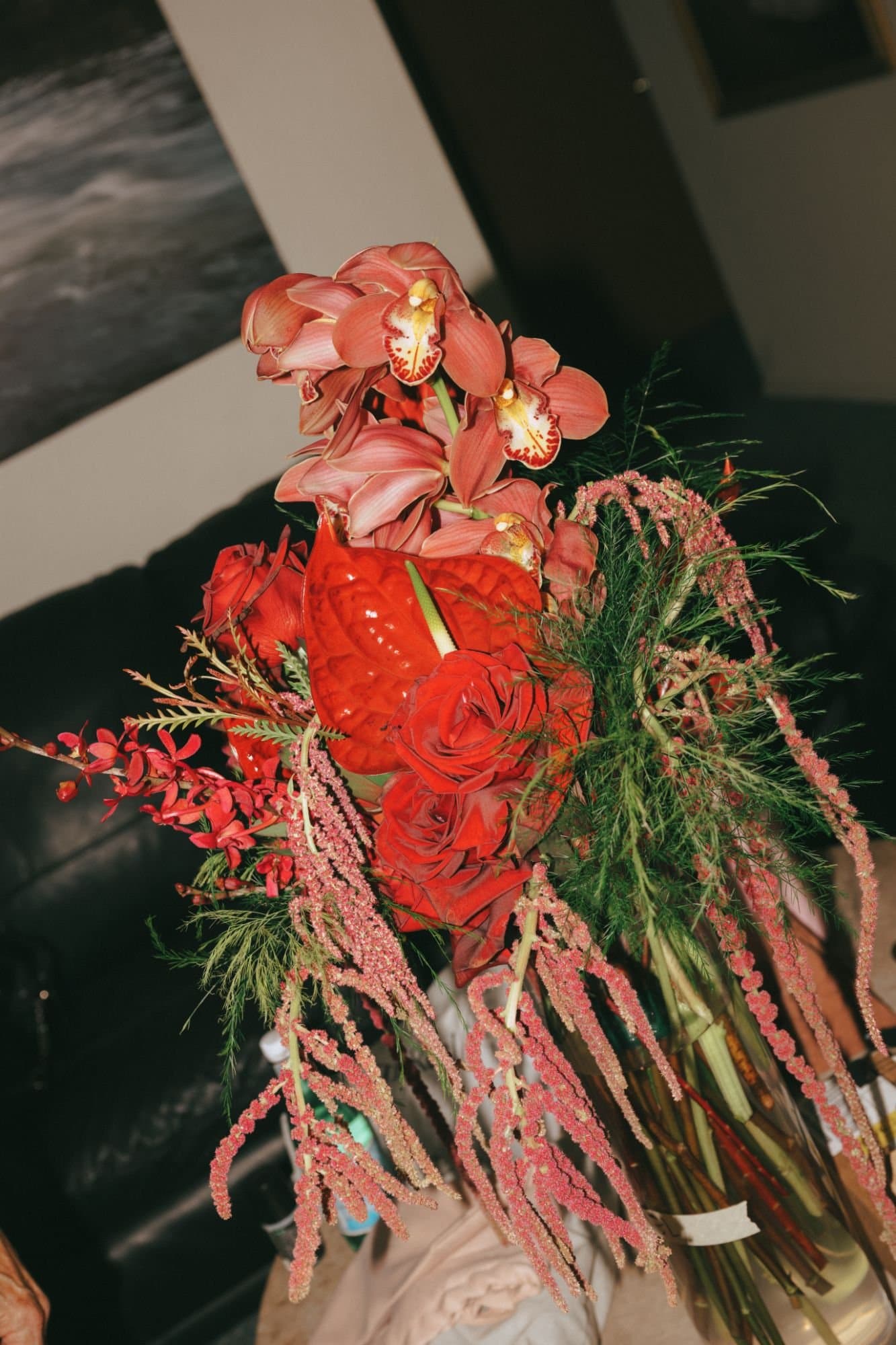 Cymbidium orchids, red anthurium and roses with hanging amaranthus