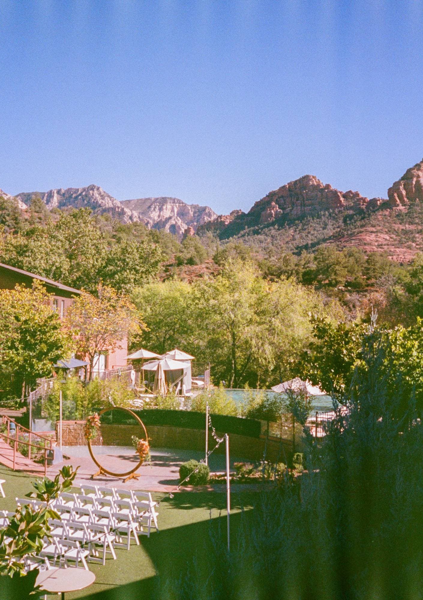 The Amara lawn set for the ceremony, white chairs facing a circular wooden arch beneath the red rocks, on film