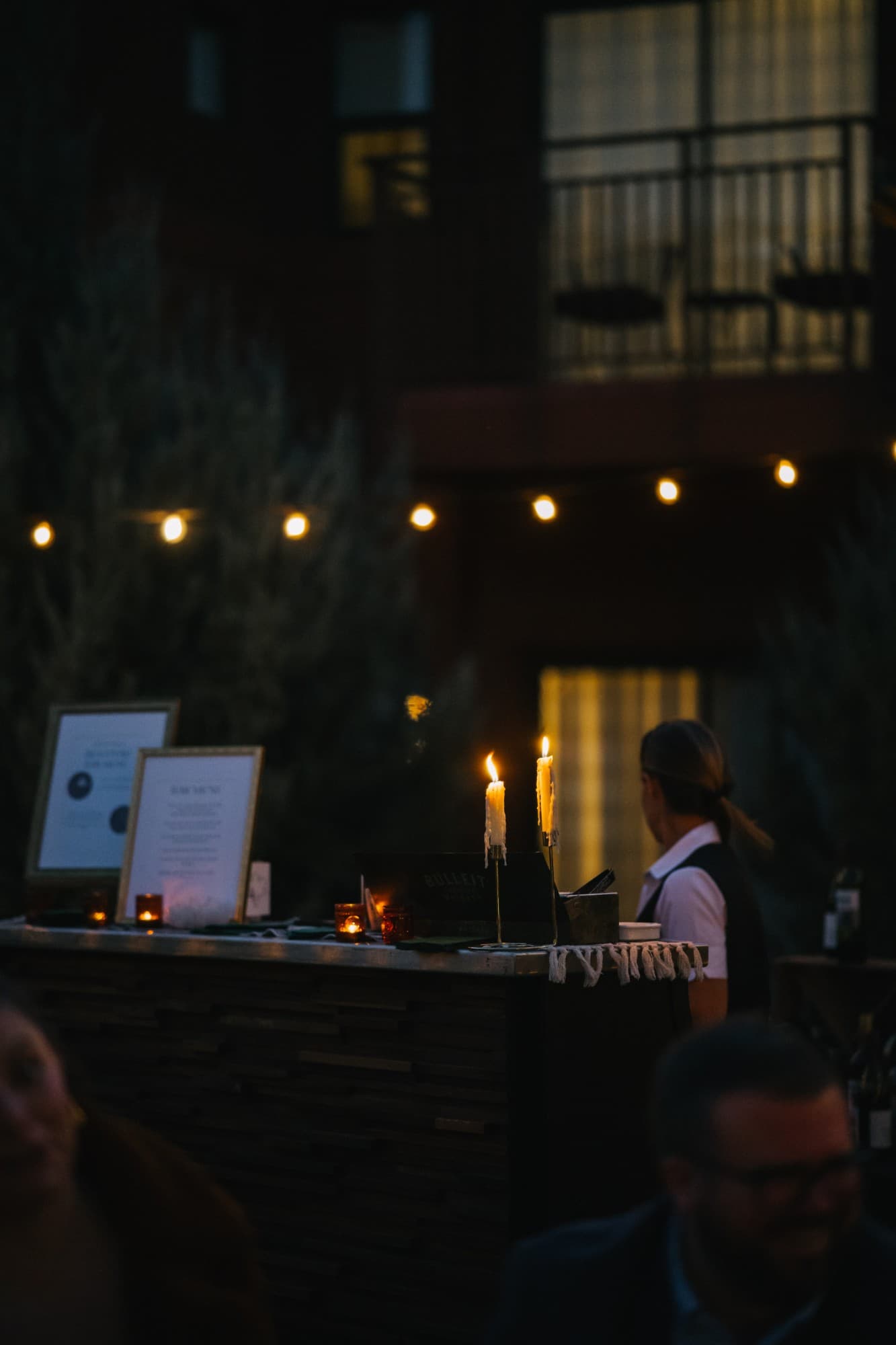 Taper candles glowing on the bar at dusk