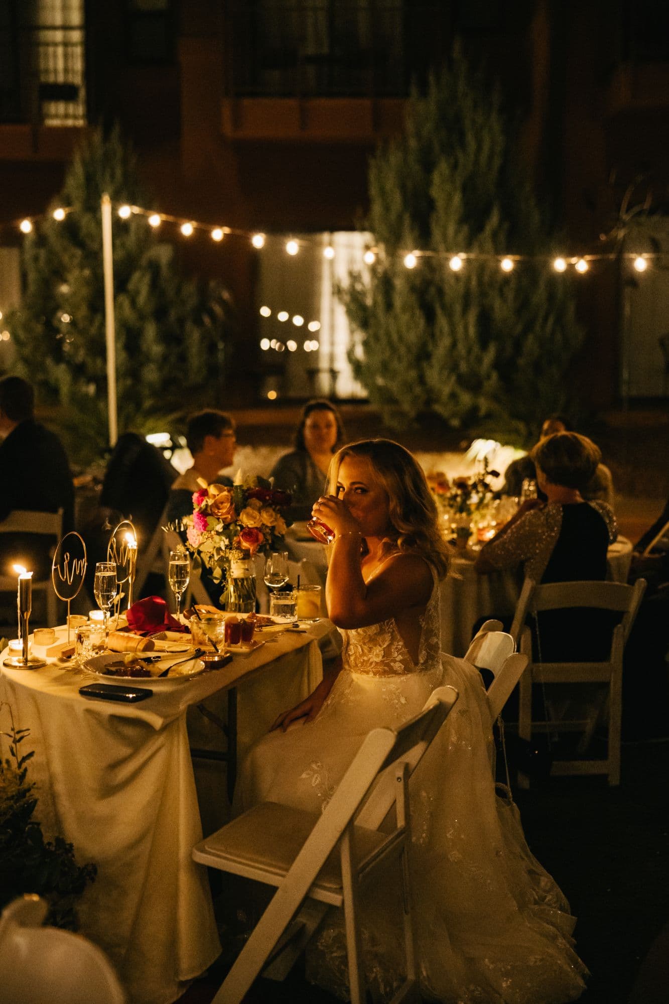 Jenna sipping a drink at the sweetheart table by candlelight
