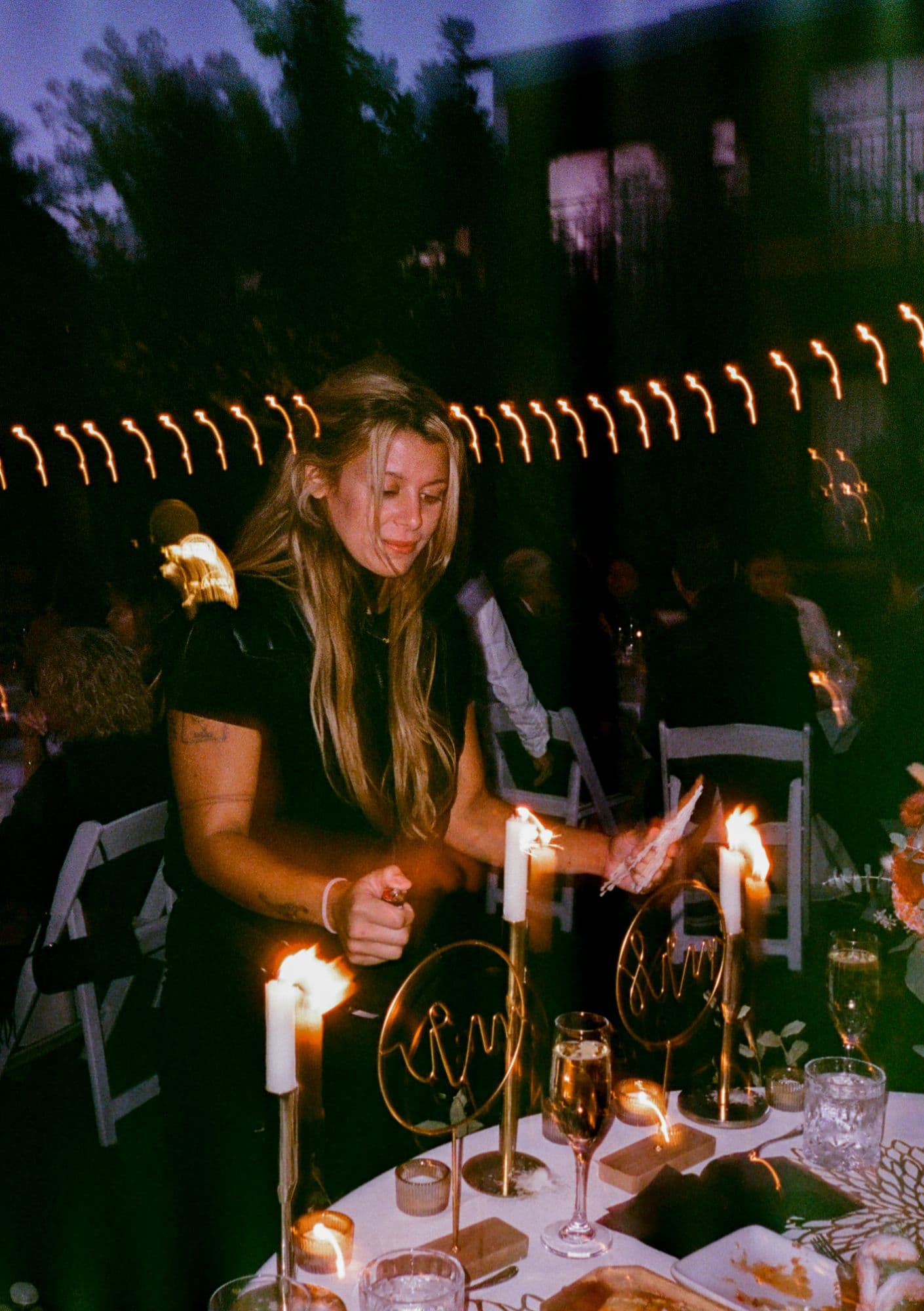 Arabella relighting taper candles at dusk, on film