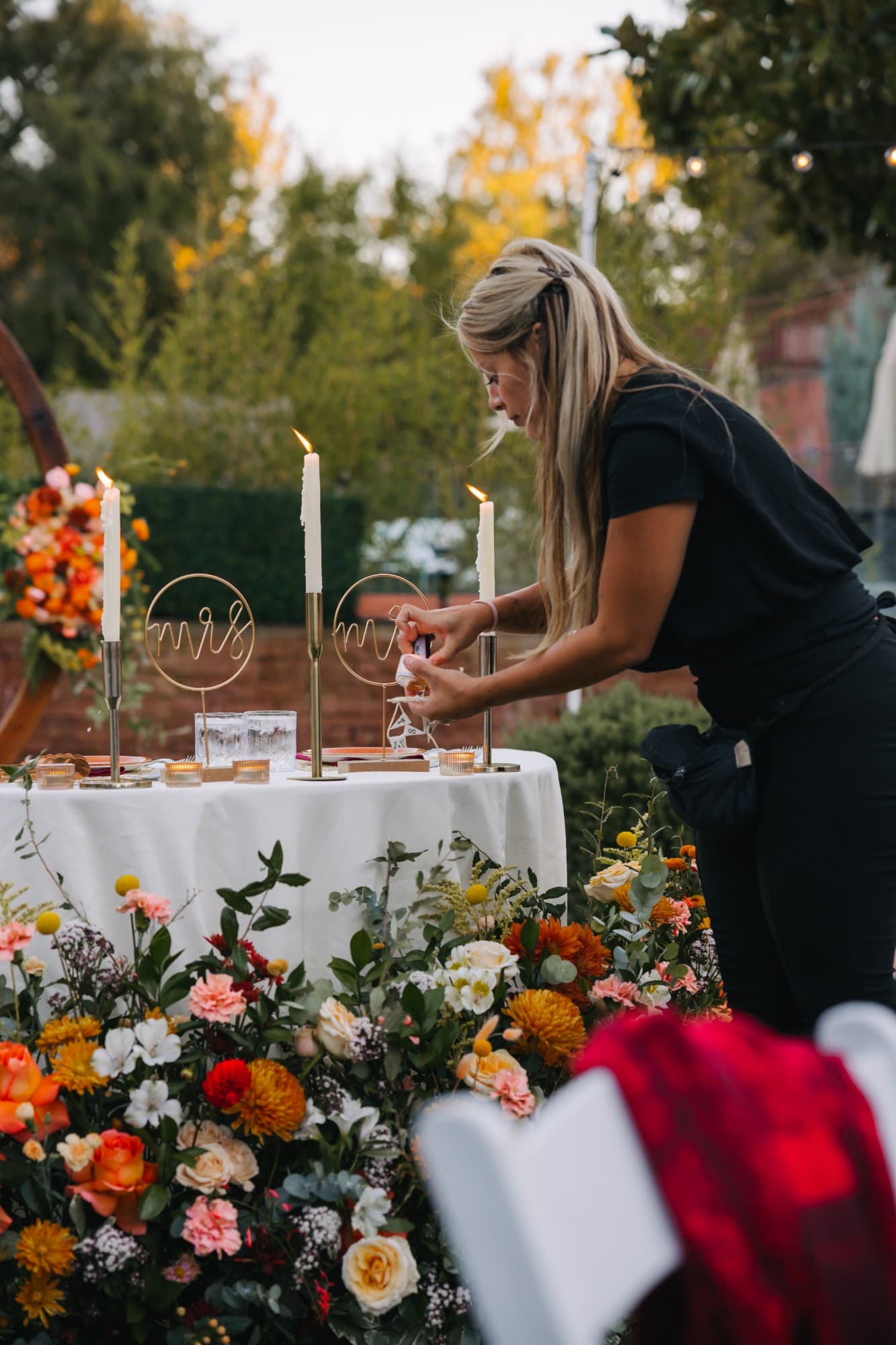 Arabella lighting the sweetheart table candles beside the Mr. and Mrs. signs