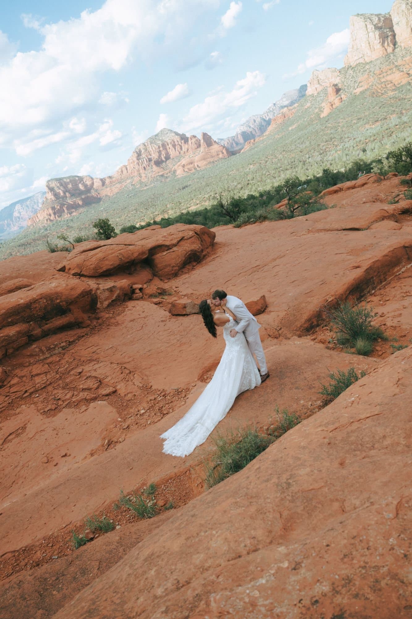 A groom dipping his bride into a kiss on the red rocks of Sedona