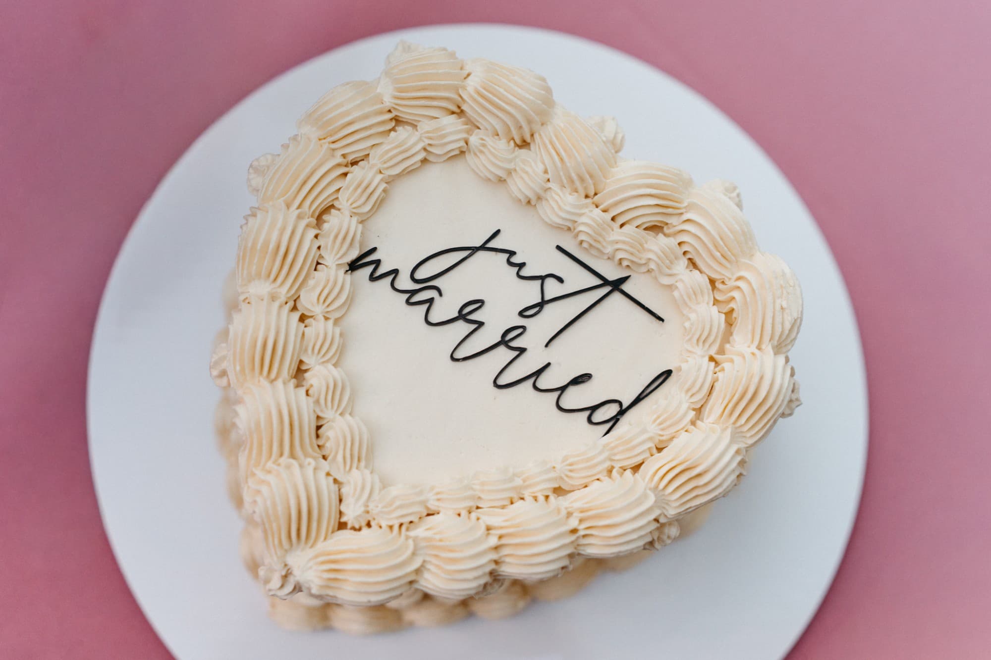 A heart-shaped buttercream cake topped with a 'just married' script