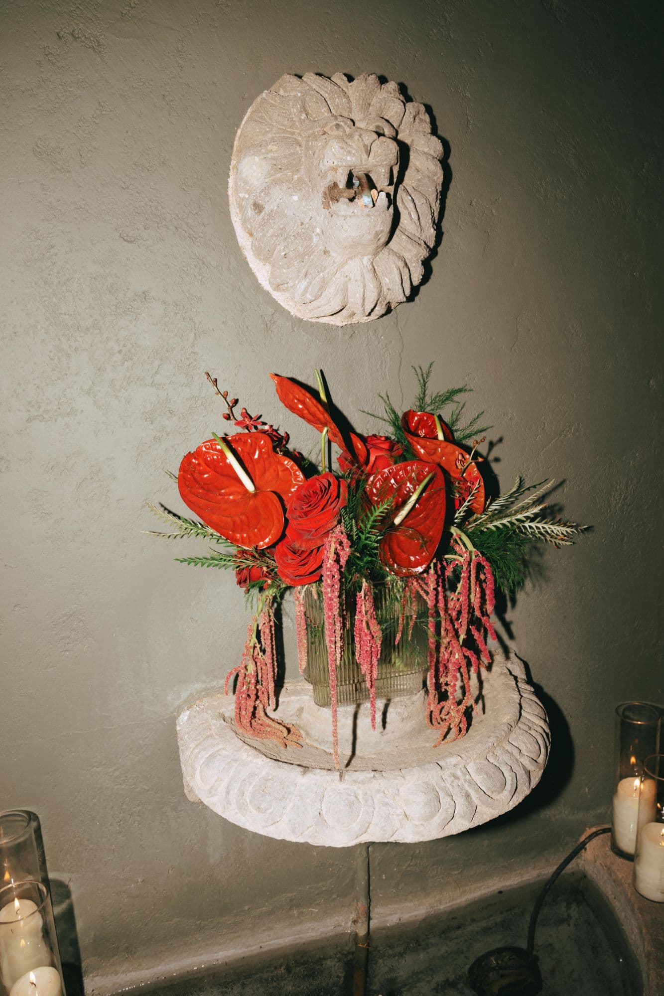 Red anthurium, rose and hanging amaranth arrangement in a stone lion fountain
