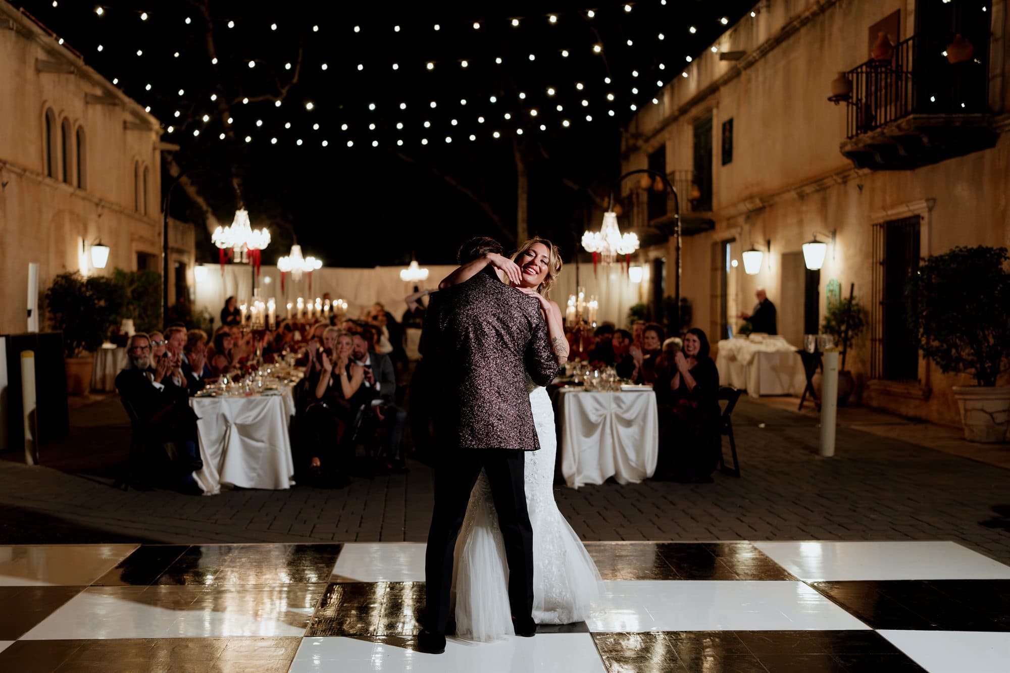 Sarah and Grant's first dance on the black-and-white dance floor under string lights