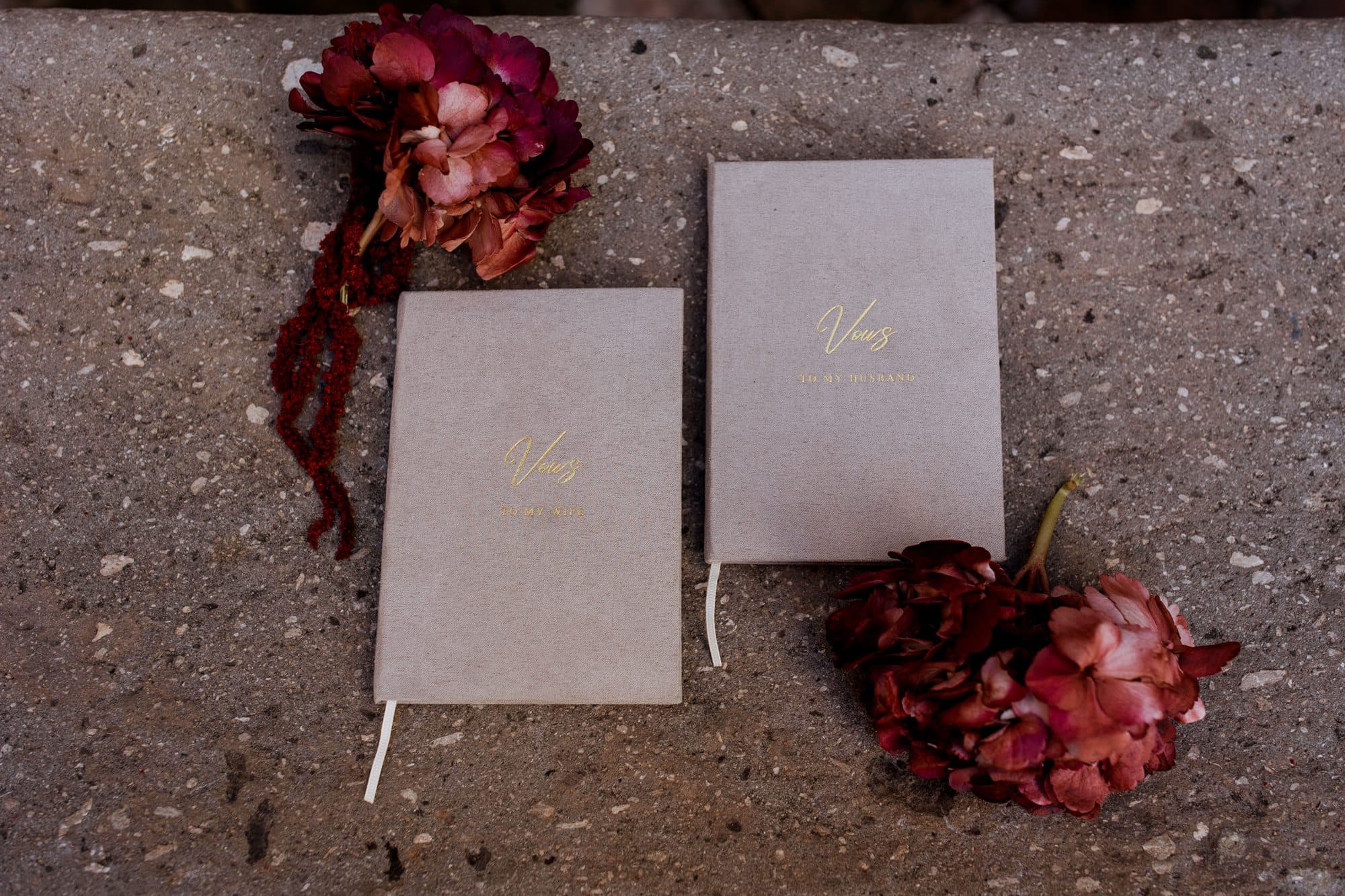 Vow books beside dried burgundy florals and red amaranthus