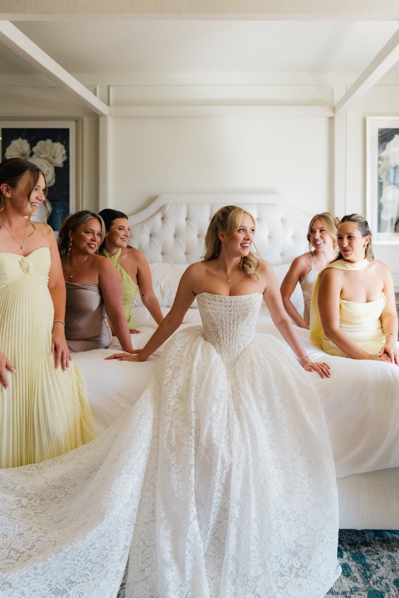Sophia with her bridesmaids in soft yellow, champagne and sage on a white canopy bed