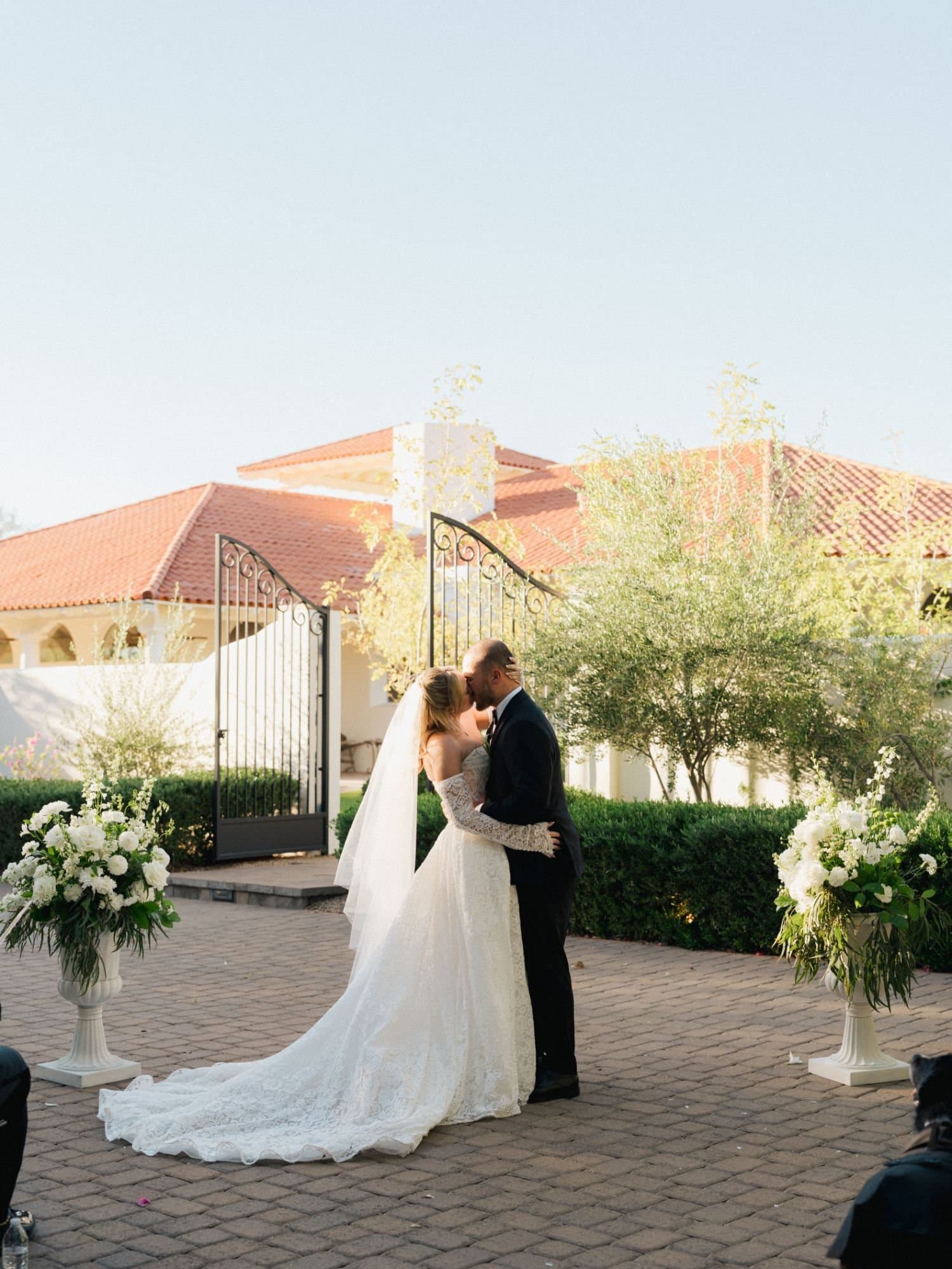 Sophia and Zachary's first kiss before the open iron gates and terracotta roofline