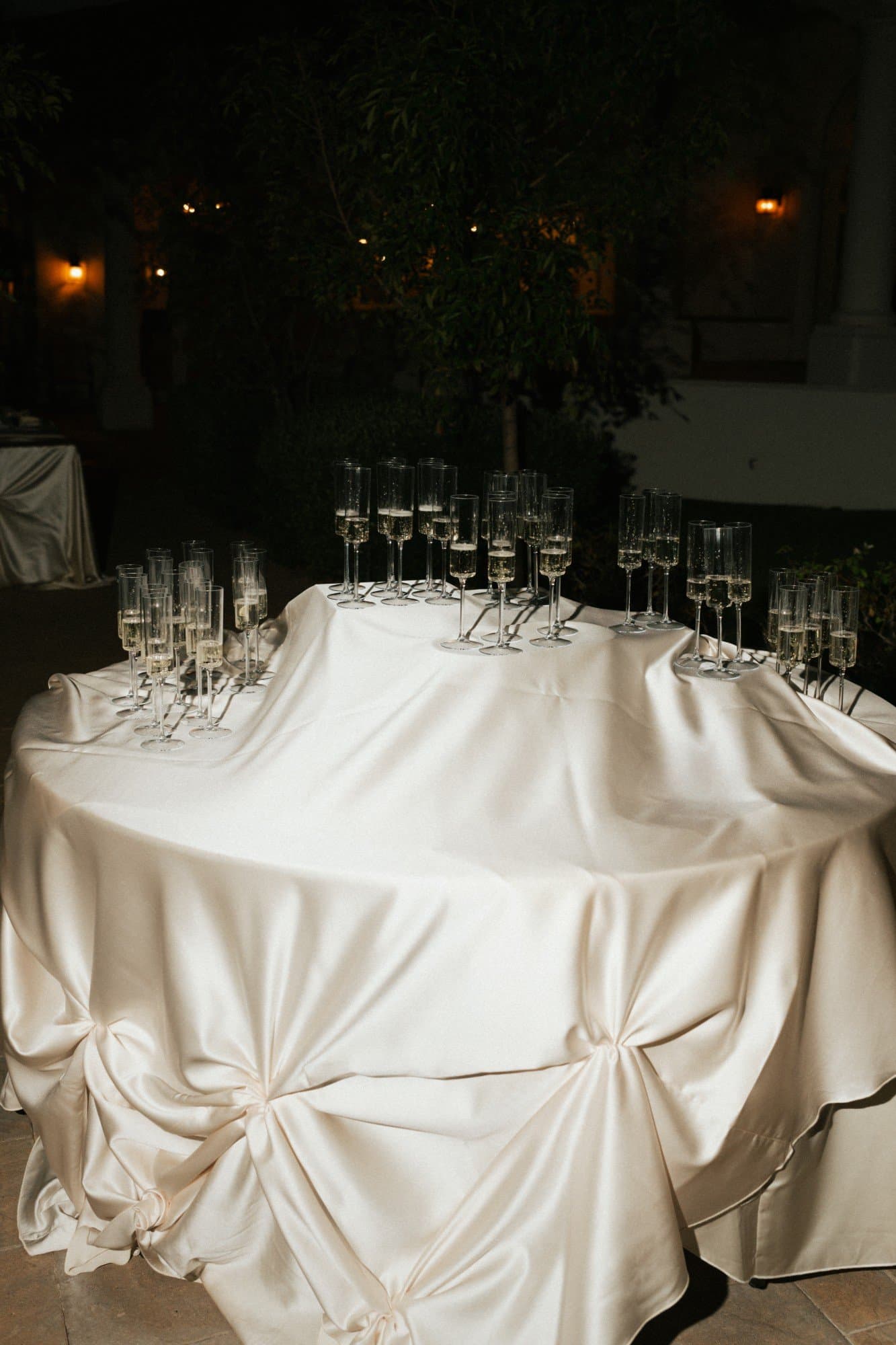 Champagne flutes on an ivory satin table gathered into soft knots