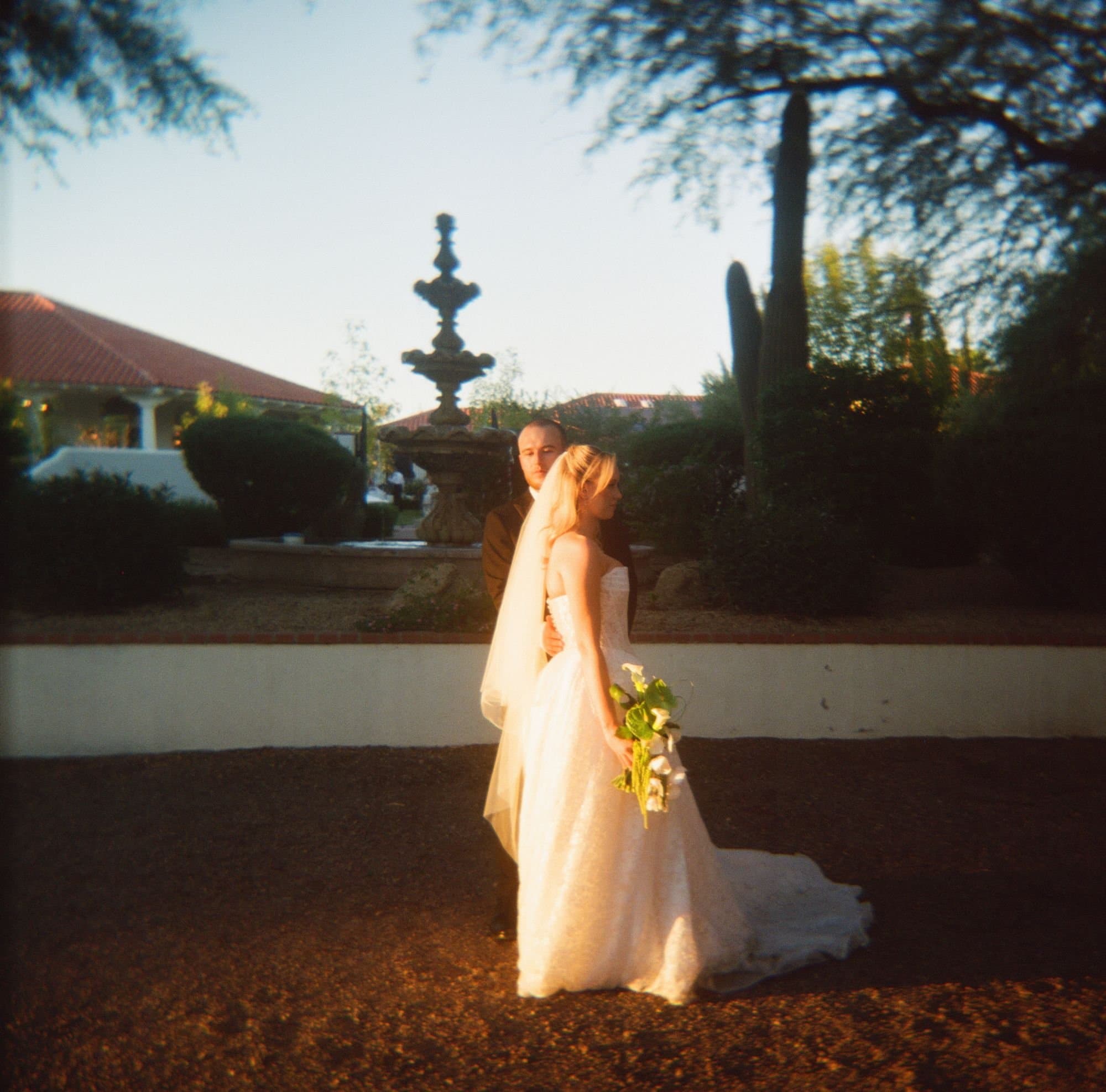 Sophia and Zachary in warm film light before the courtyard fountain and saguaros