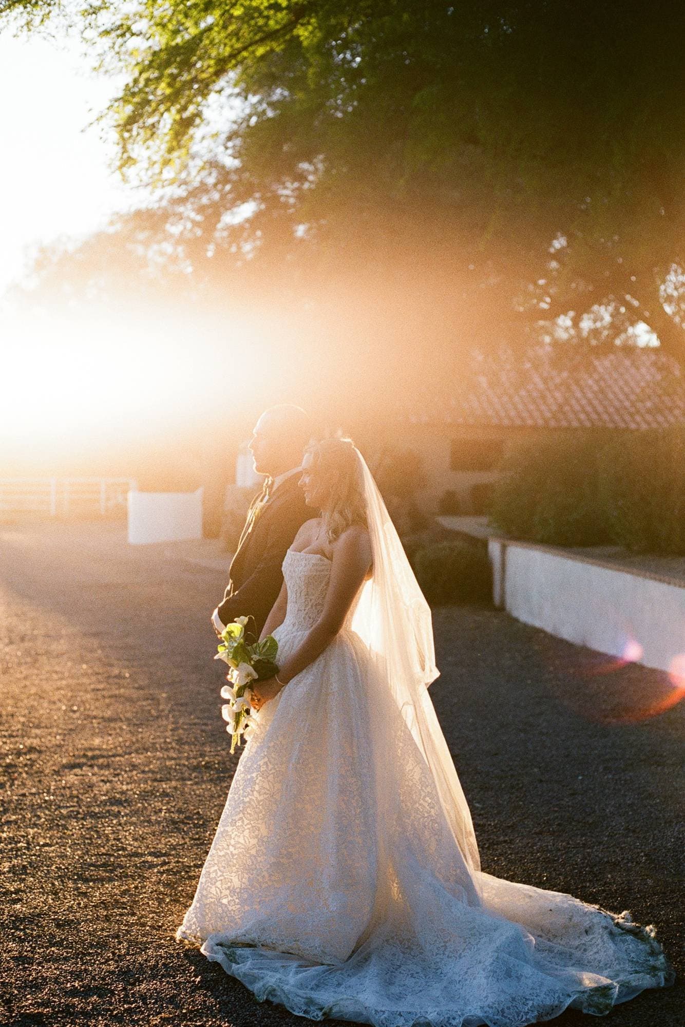 Sophia and Zachary in golden sunset light at Hozho Alameda Ranch, her lace gown and veil glowing