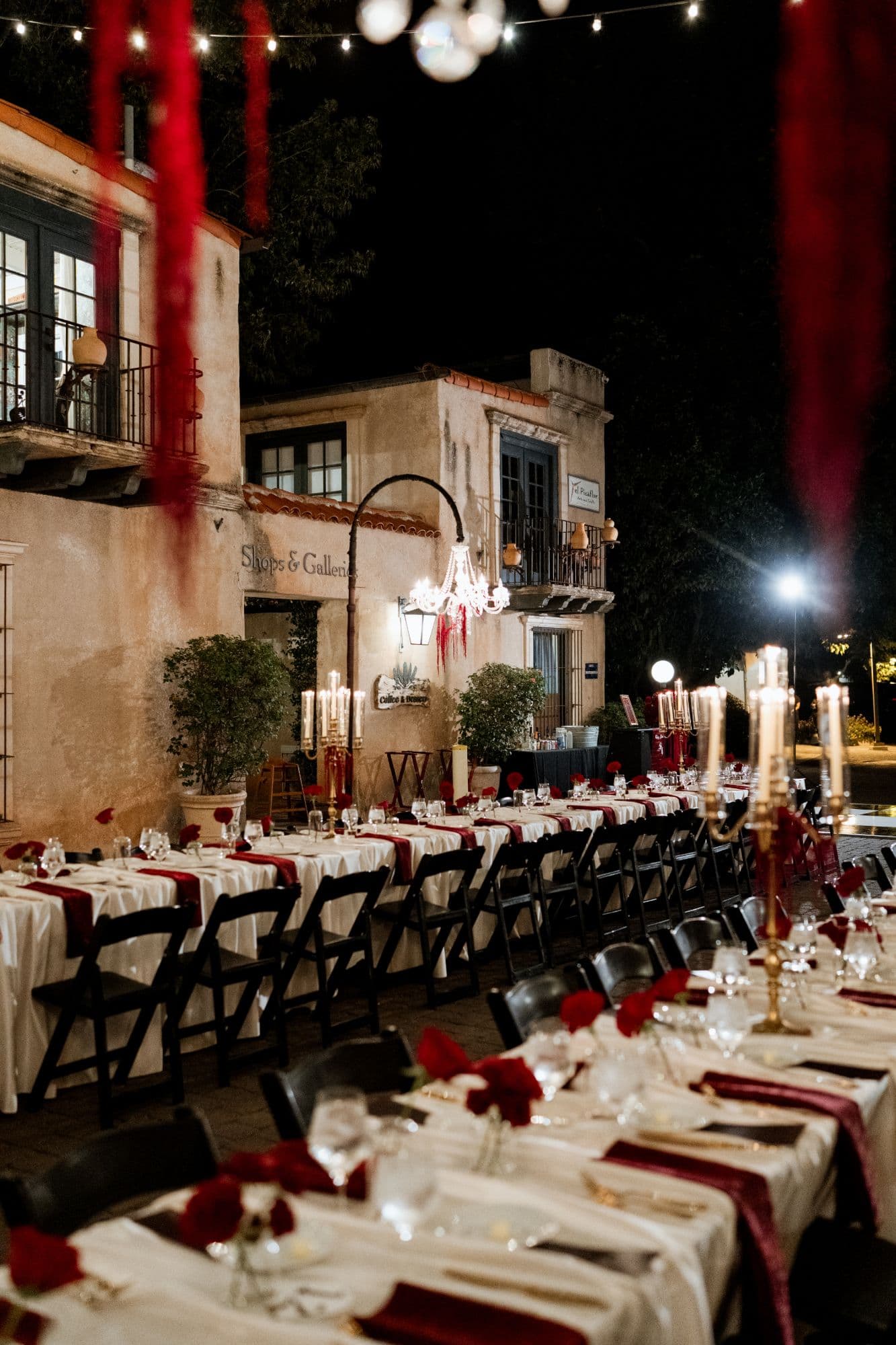 Long candlelit tables with gold candelabras and red roses in a Tlaquepaque courtyard at night