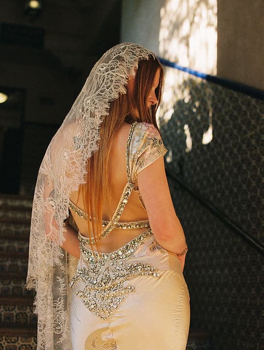 Bride in a lace mantilla veil and beaded champagne gown on the stairs at Tlaquepaque, Sedona