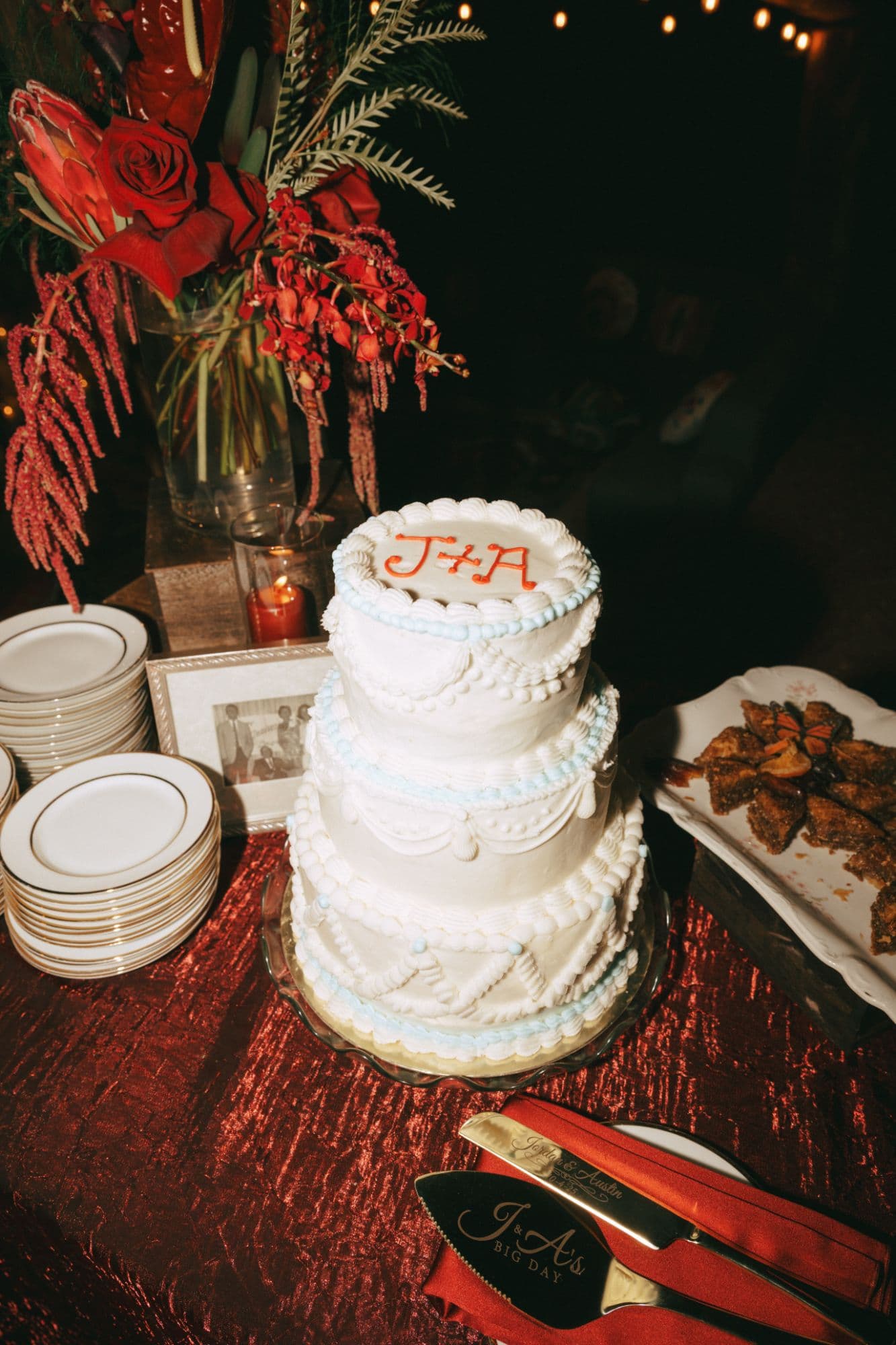 Three-tier vintage piped buttercream wedding cake with red monogram and engraved cake server
